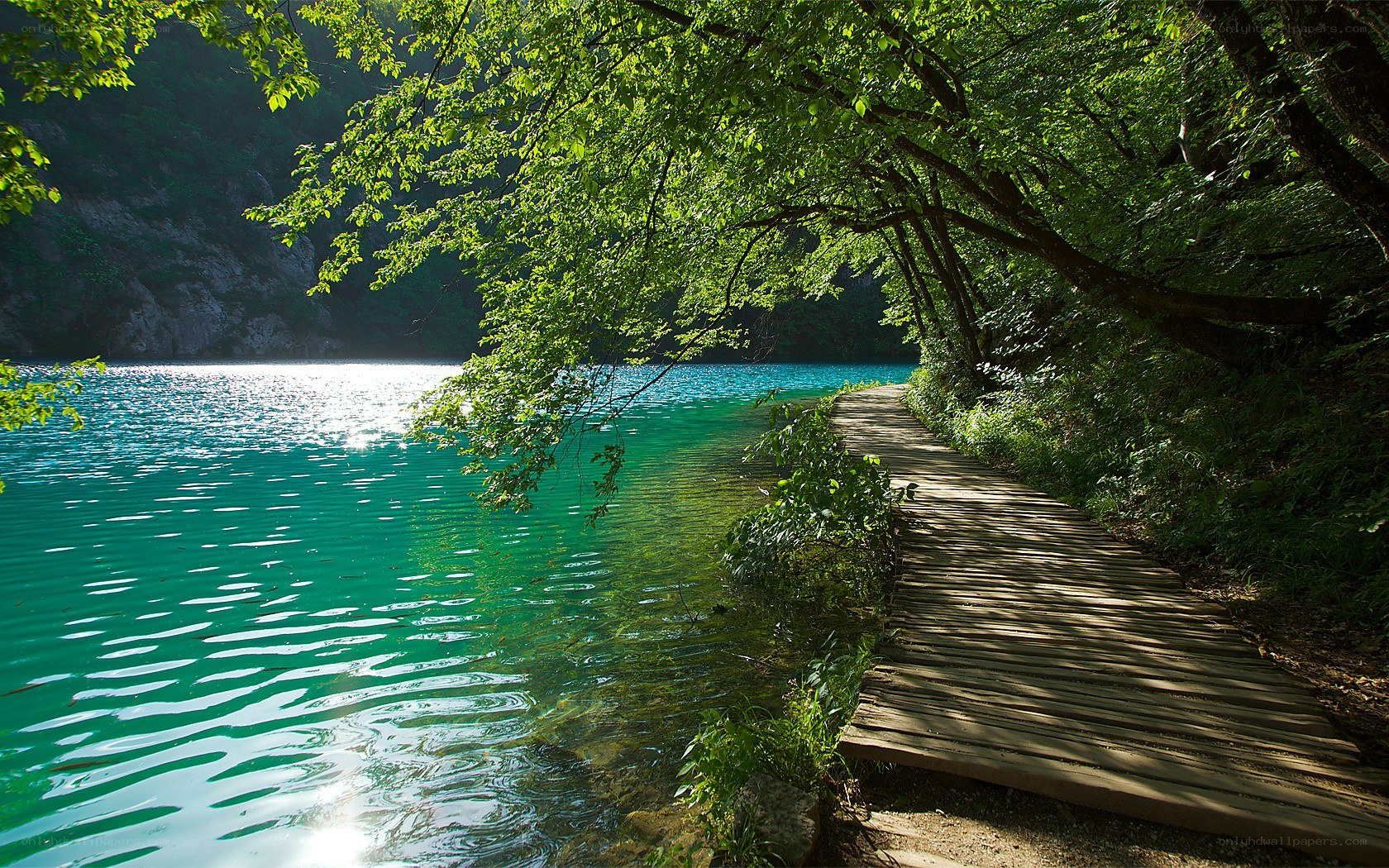 Wooden path by turquoise lake