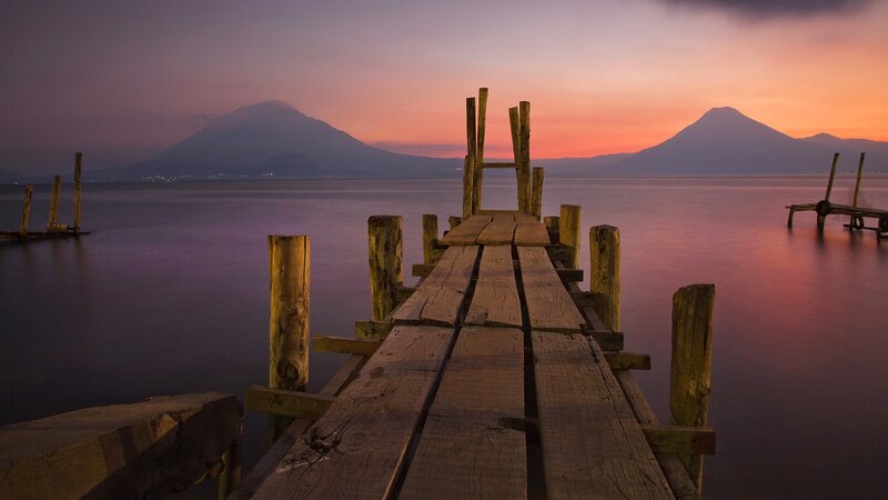 Wooden pier at sunset with volcanoes