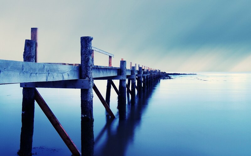 Wooden Pier Extending into Water — Blue