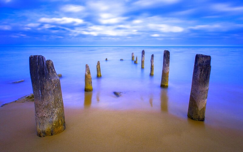 Wooden Posts in Ocean — Blue, Serene, Sunset