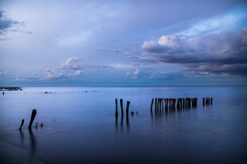 Wooden Posts in Water — Blue, Serene, Sunset