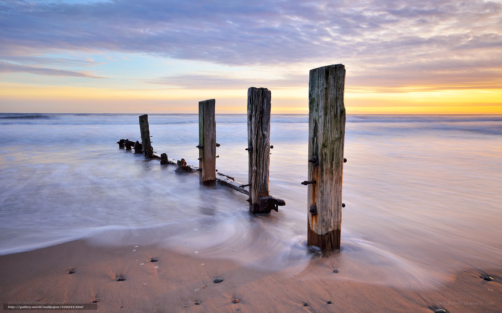 Wooden posts on beach at sunset