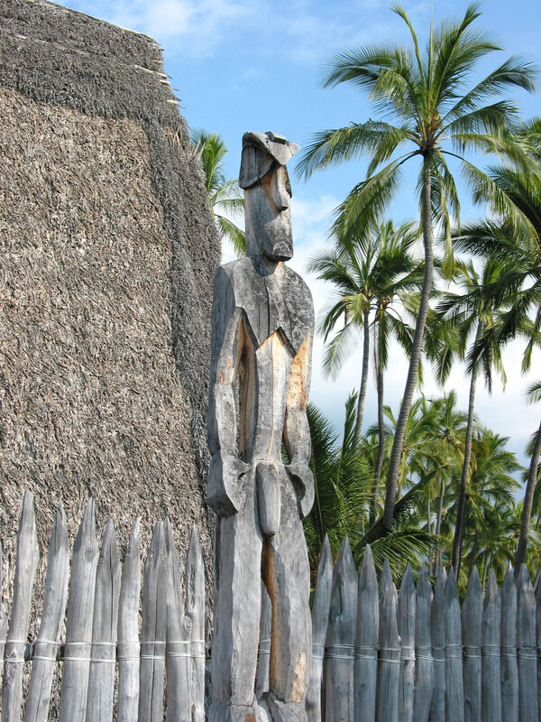 Wooden statue near thatched hut