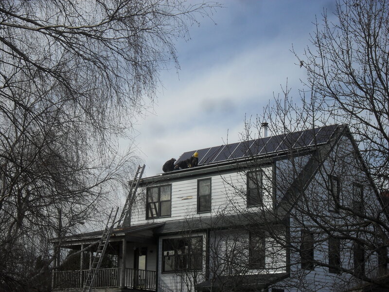 Workers installing solar panels on a house
