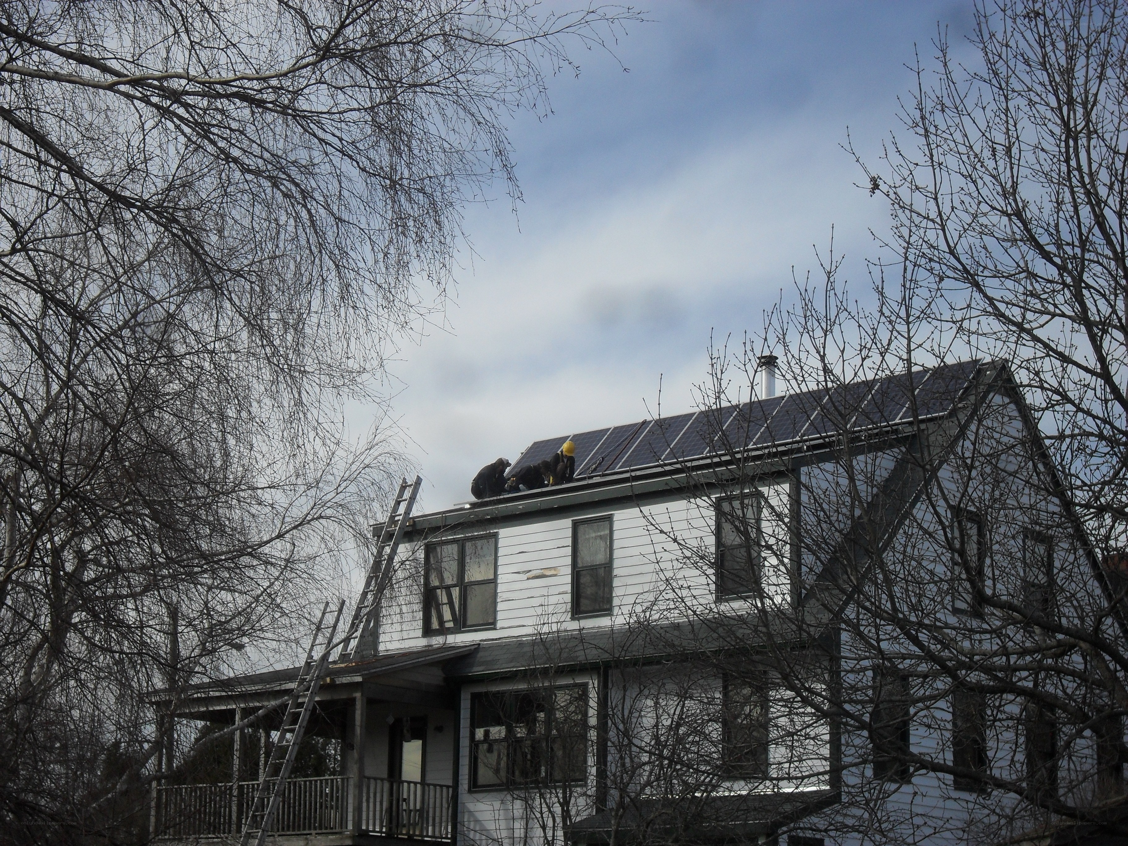 Workers installing solar panels on a house