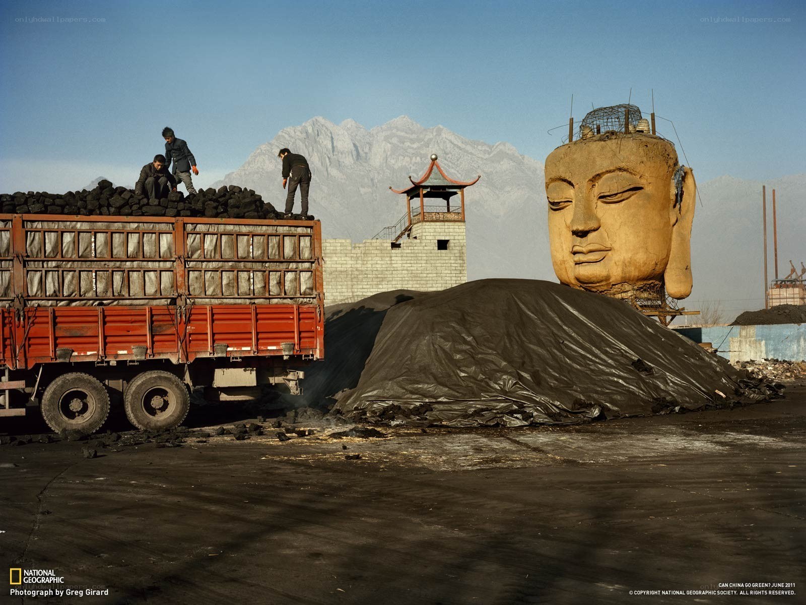 Workers near Buddha head sculpture