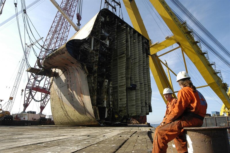Workers observing ship salvage