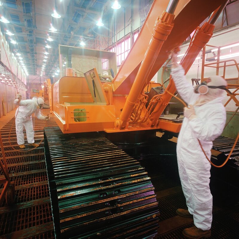 Workers painting construction equipment