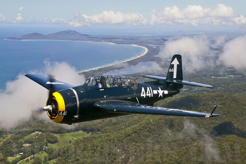 WWII-era aircraft over coastal landscape