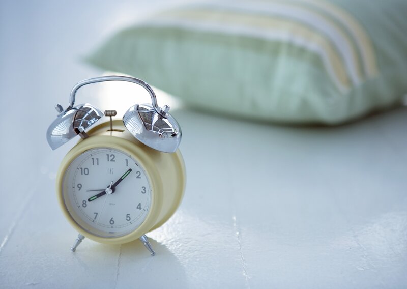 Yellow alarm clock on a bed