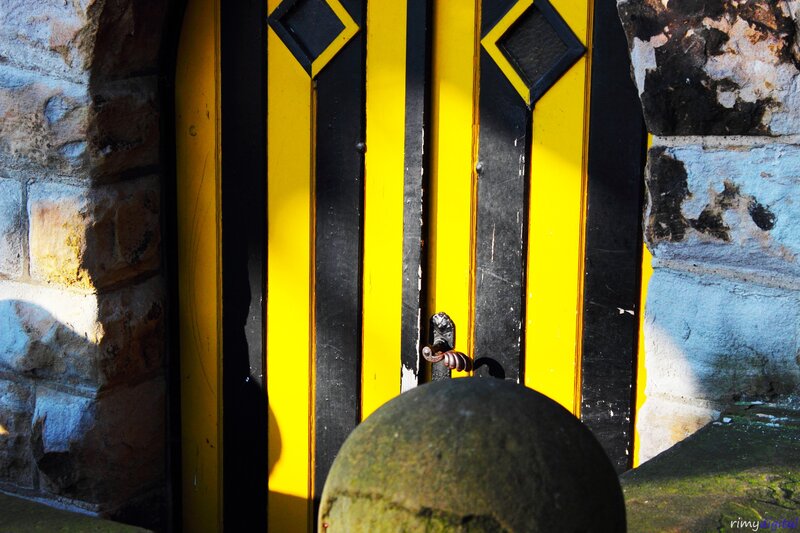 yellow and black door with stone wall