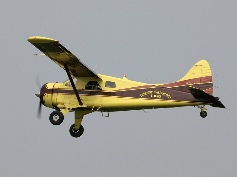 Yellow and maroon bush plane in flight