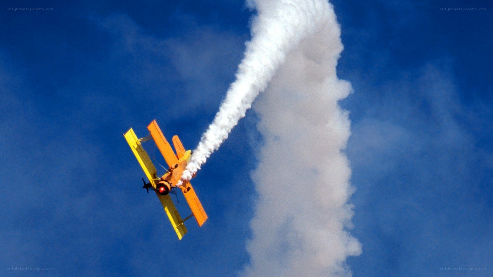 Yellow biplane performing aerobatics