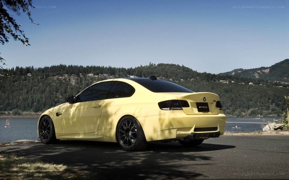yellow BMW coupe by the water