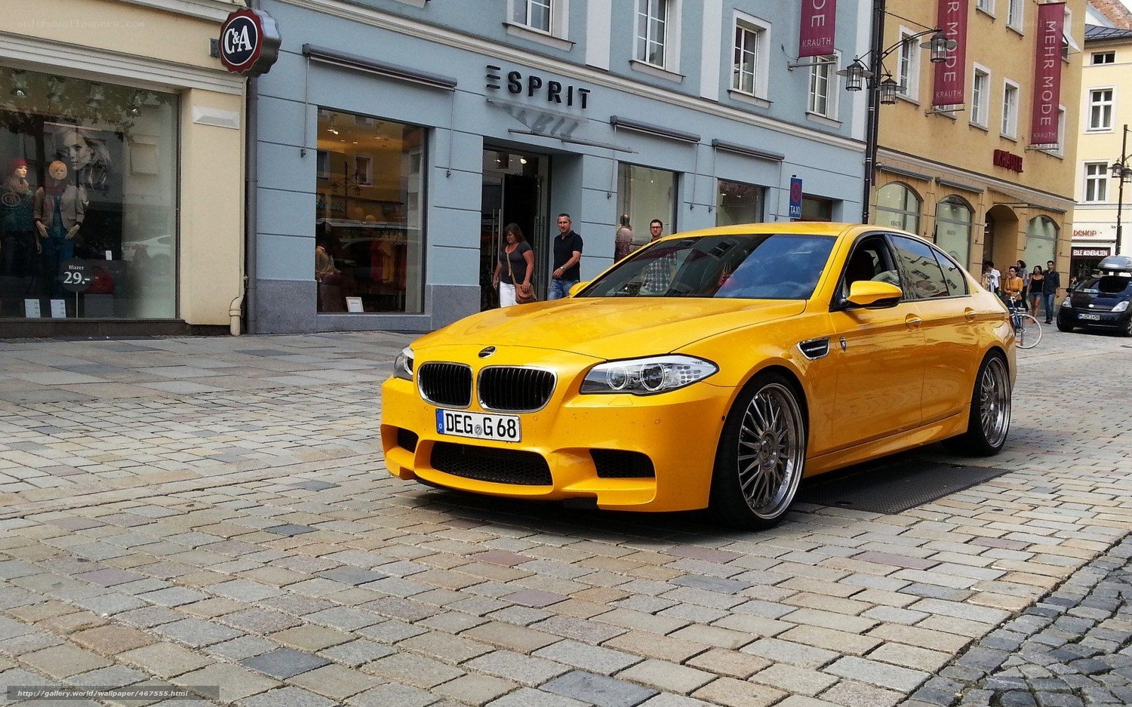 Yellow BMW M5 on cobblestone street