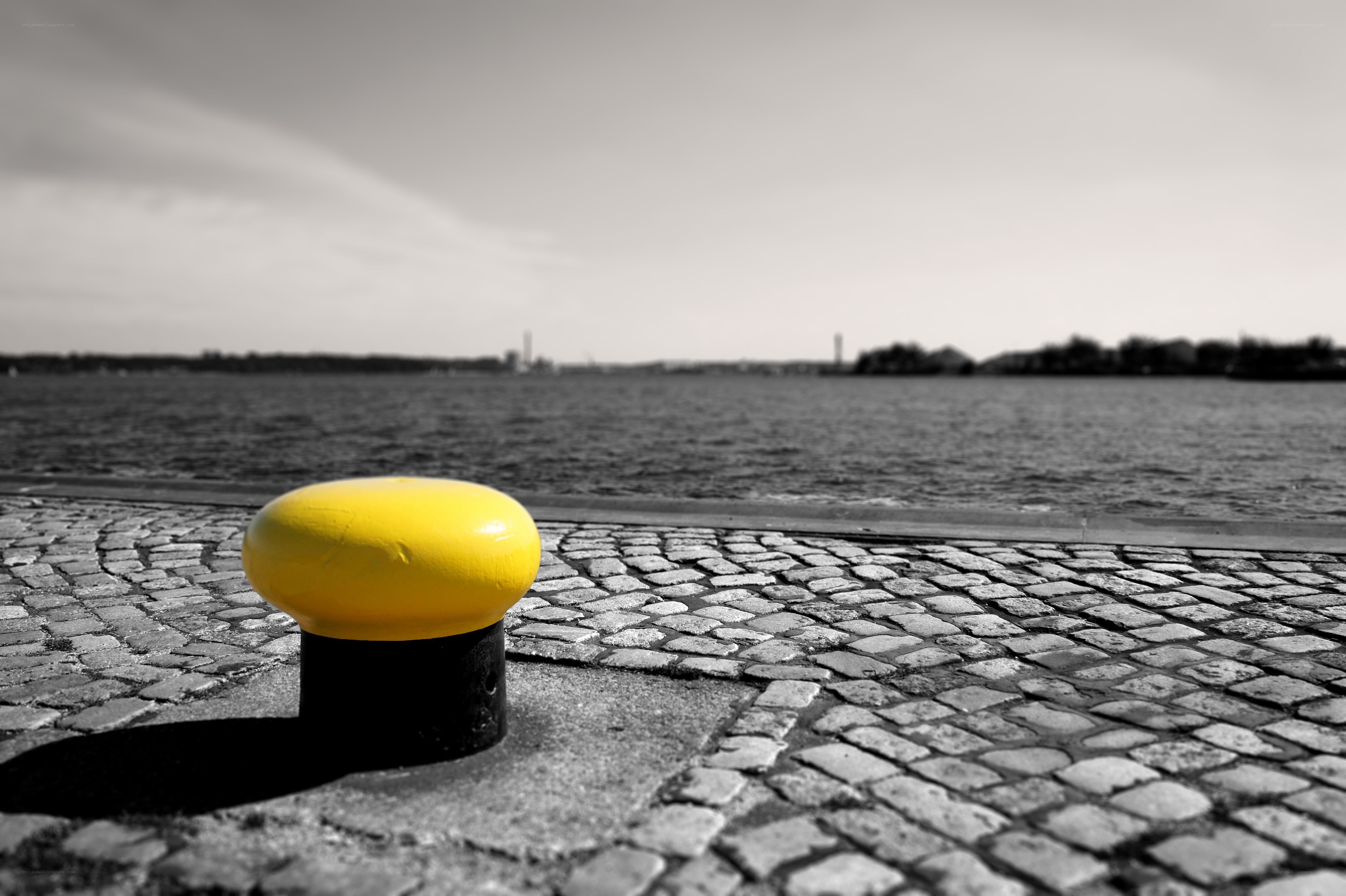 yellow bollard on cobblestone