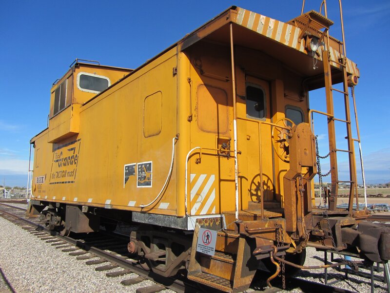 yellow caboose on train tracks