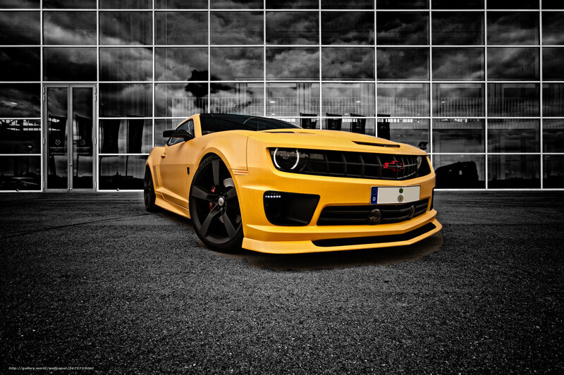 Yellow Camaro in front of glass building