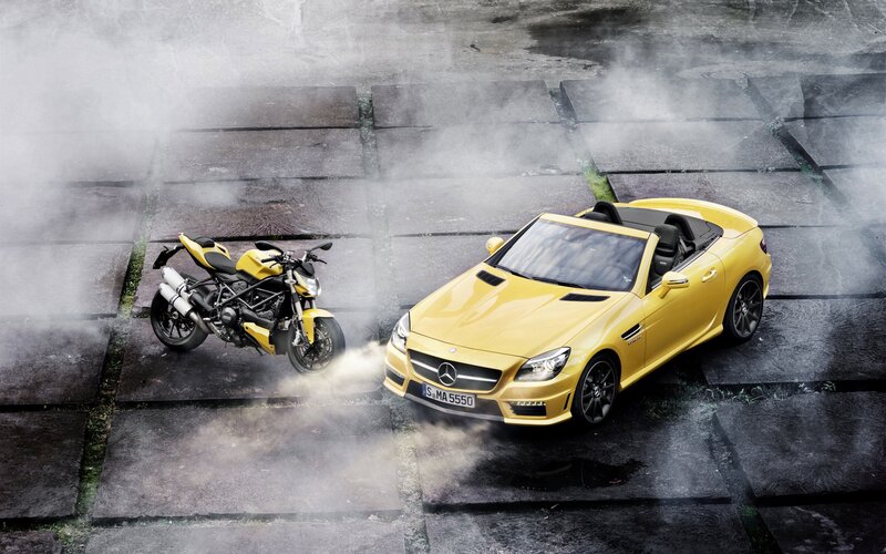 Yellow car and motorcycle on cobblestones