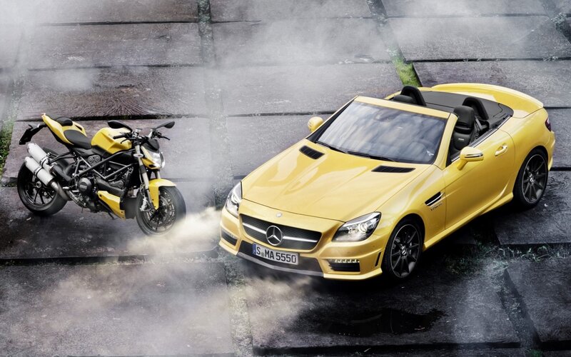 Yellow car and motorcycle on wet pavement