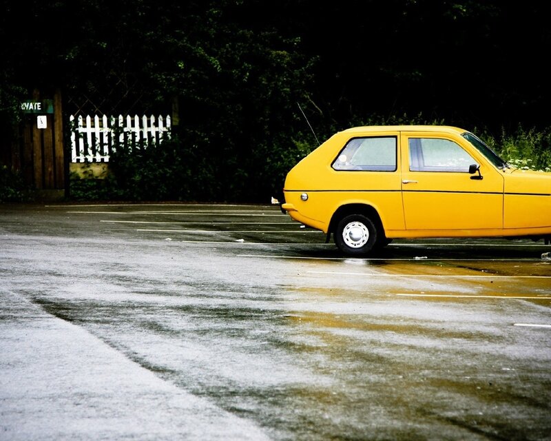 Yellow car in wet parking lot