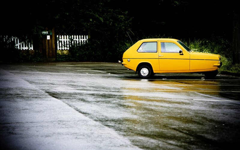 Yellow car in wet parking lot