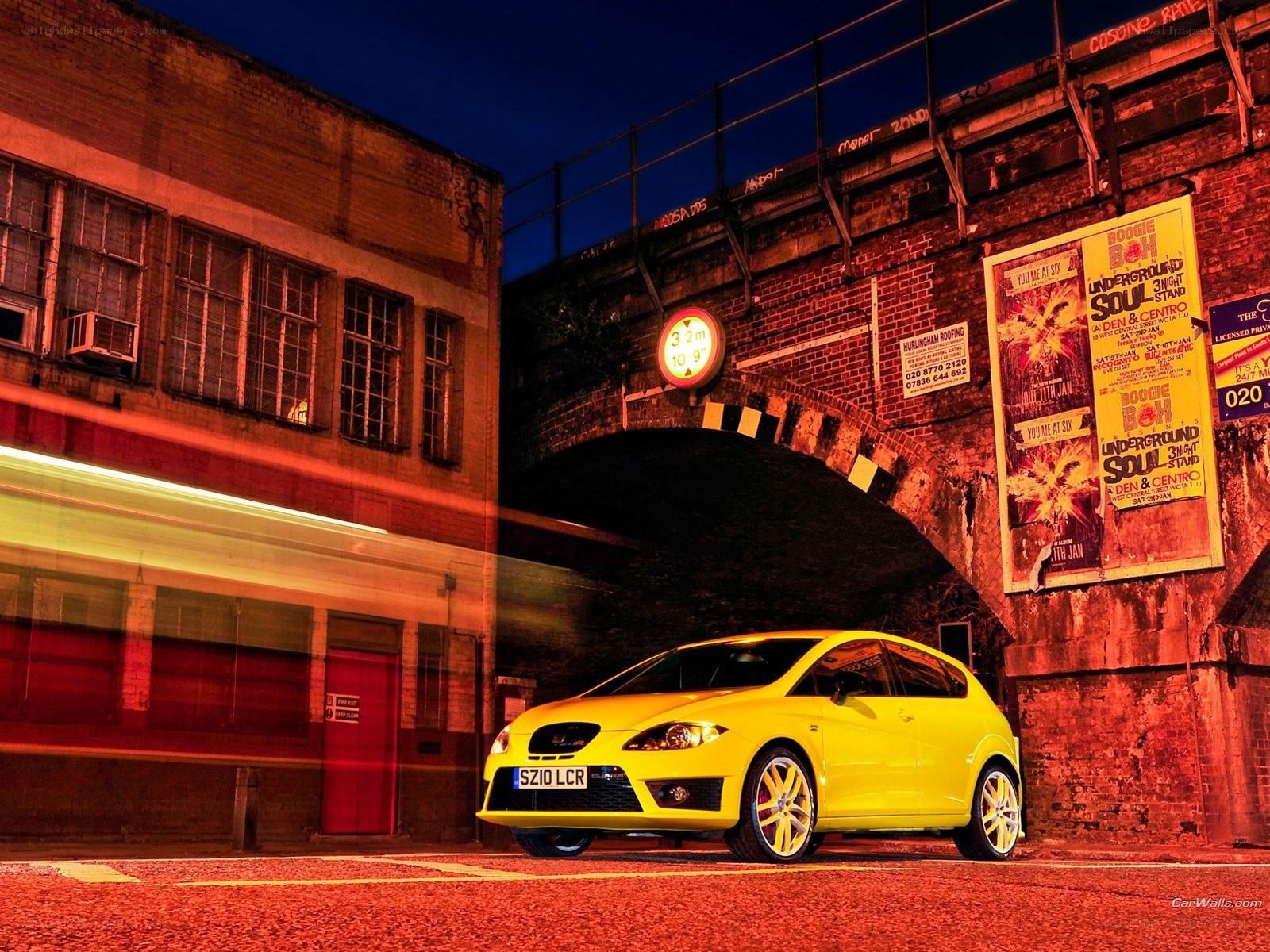 Yellow car under a bridge at night