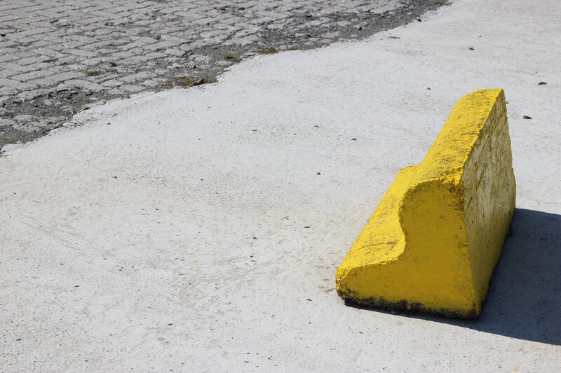 Yellow concrete barrier on pavement