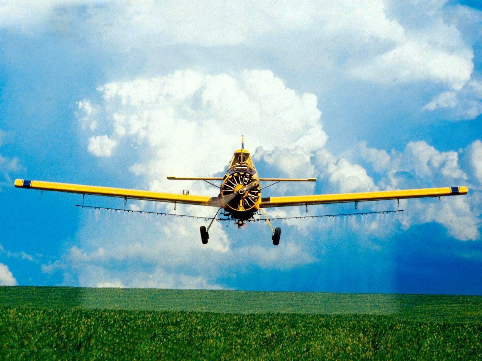 Yellow crop duster flying over field