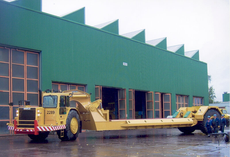 Yellow heavy machinery outside a green building
