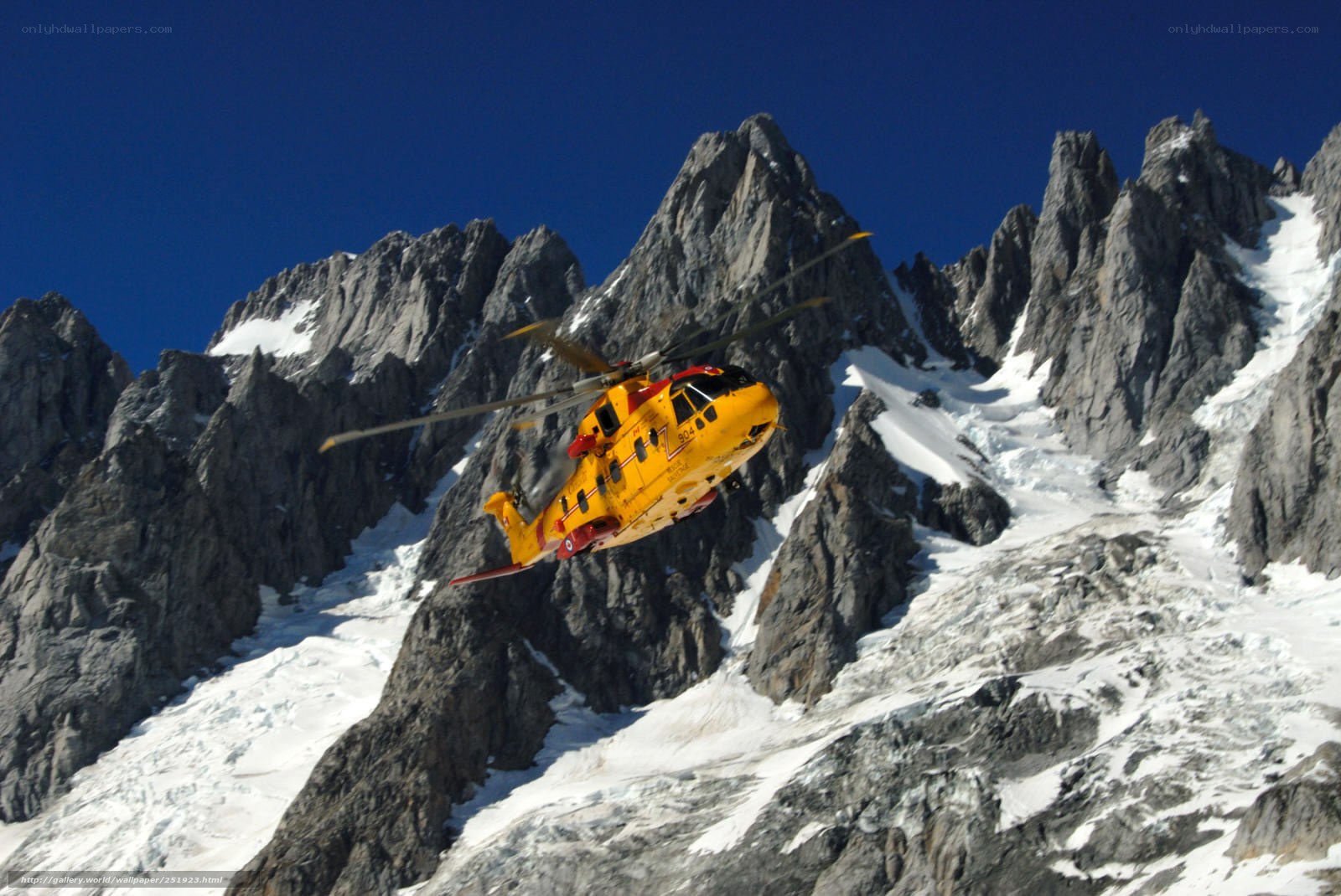 Yellow helicopter over snowy mountains