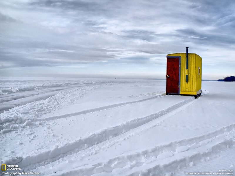 Yellow ice fishing hut on frozen lake
