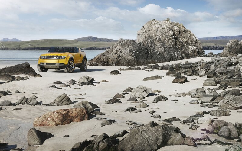 Yellow Land Rover on a rocky beach