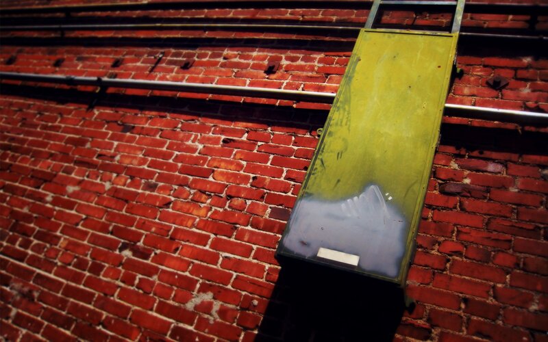 Yellow Metal Box on Brick Wall