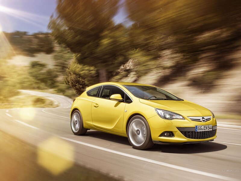 Yellow Opel Astra driving on road