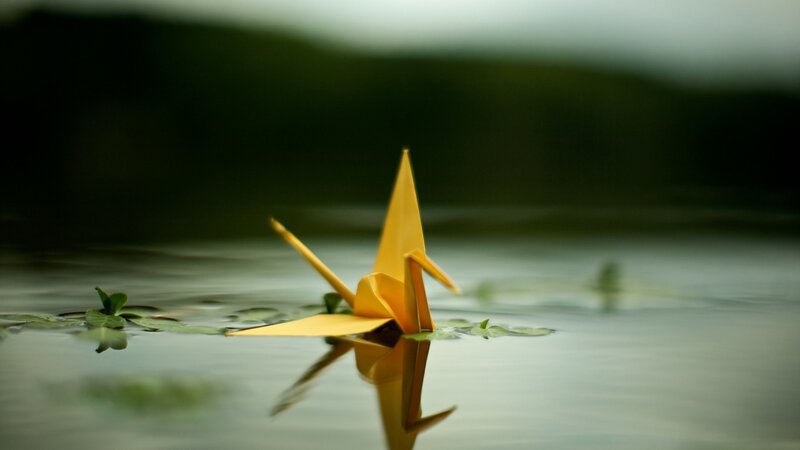 Yellow origami crane on water