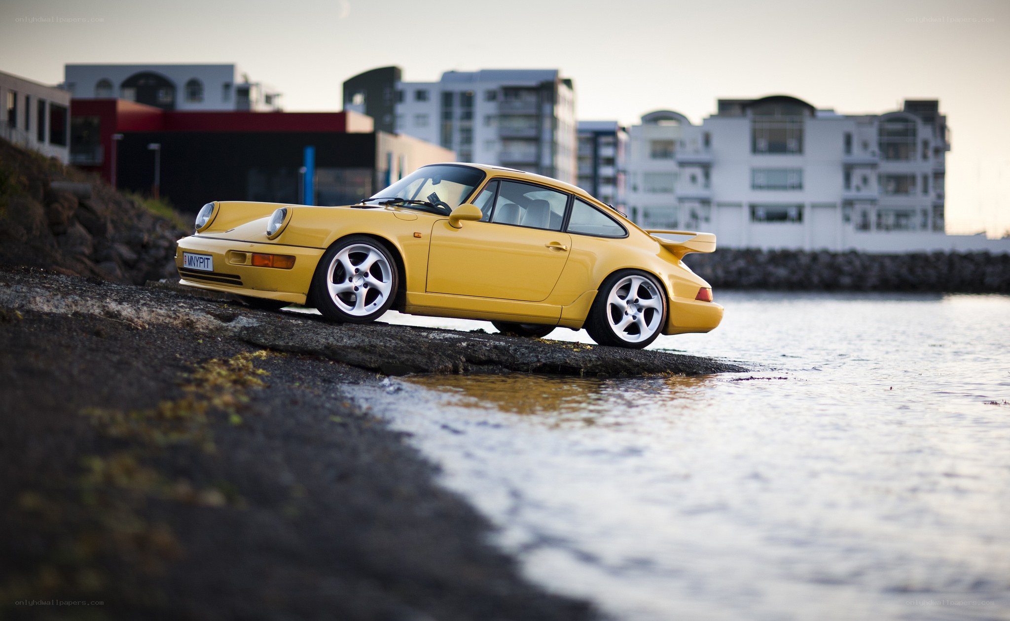 Yellow Porsche on a rocky shore