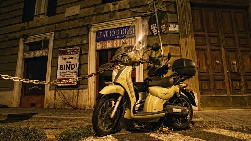 Yellow scooter outside theater at night