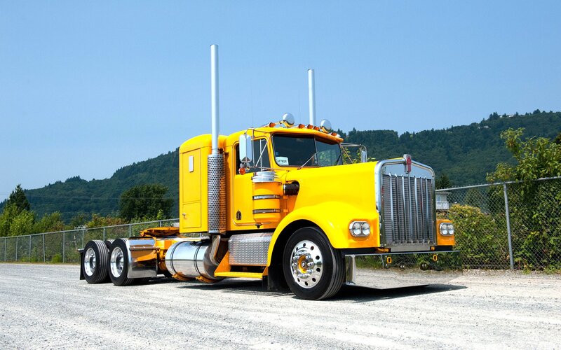 yellow semi-truck on gravel