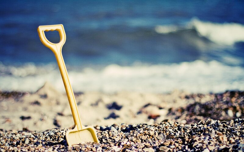 Yellow shovel on a pebble beach
