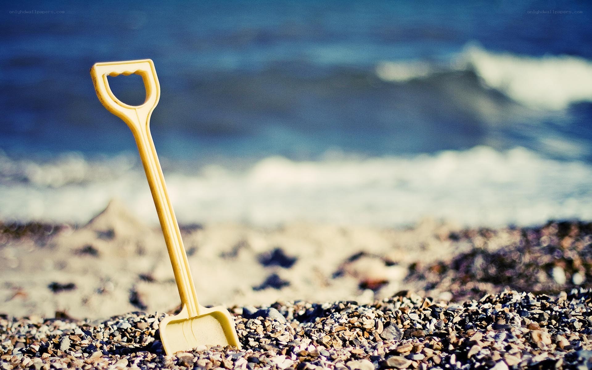 Yellow shovel on a pebble beach