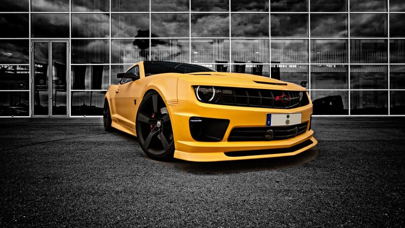 Yellow sports car in front of glass building