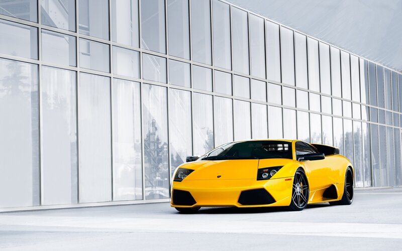 Yellow sports car in front of glass building