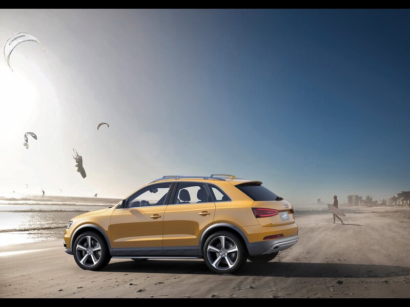 Yellow SUV on beach with kitesurfers