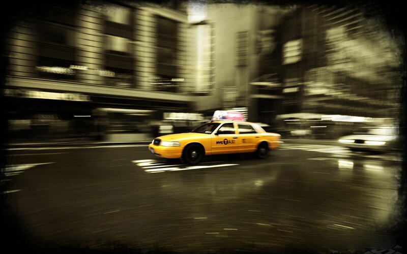 Yellow taxi in motion on city street