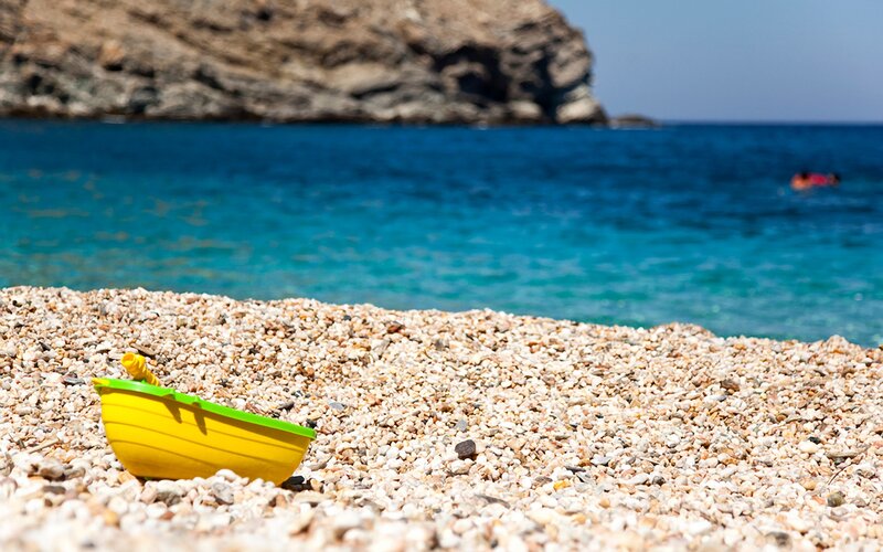 Yellow toy boat on pebble beach