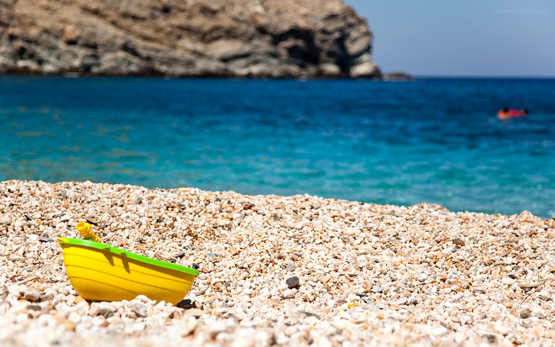 Yellow toy boat on pebble beach