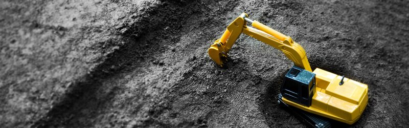 Yellow toy excavator on dirt
