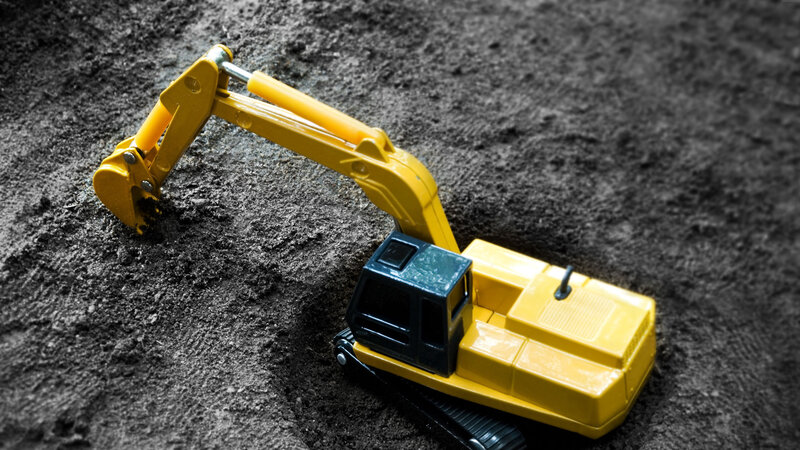 Yellow toy excavator on dirt