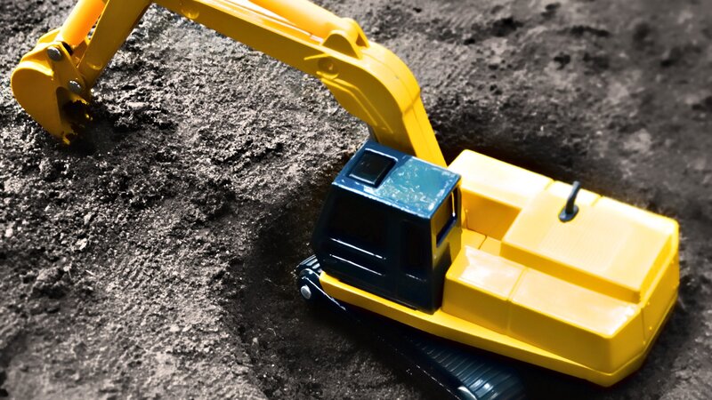 Yellow toy excavator on dirt